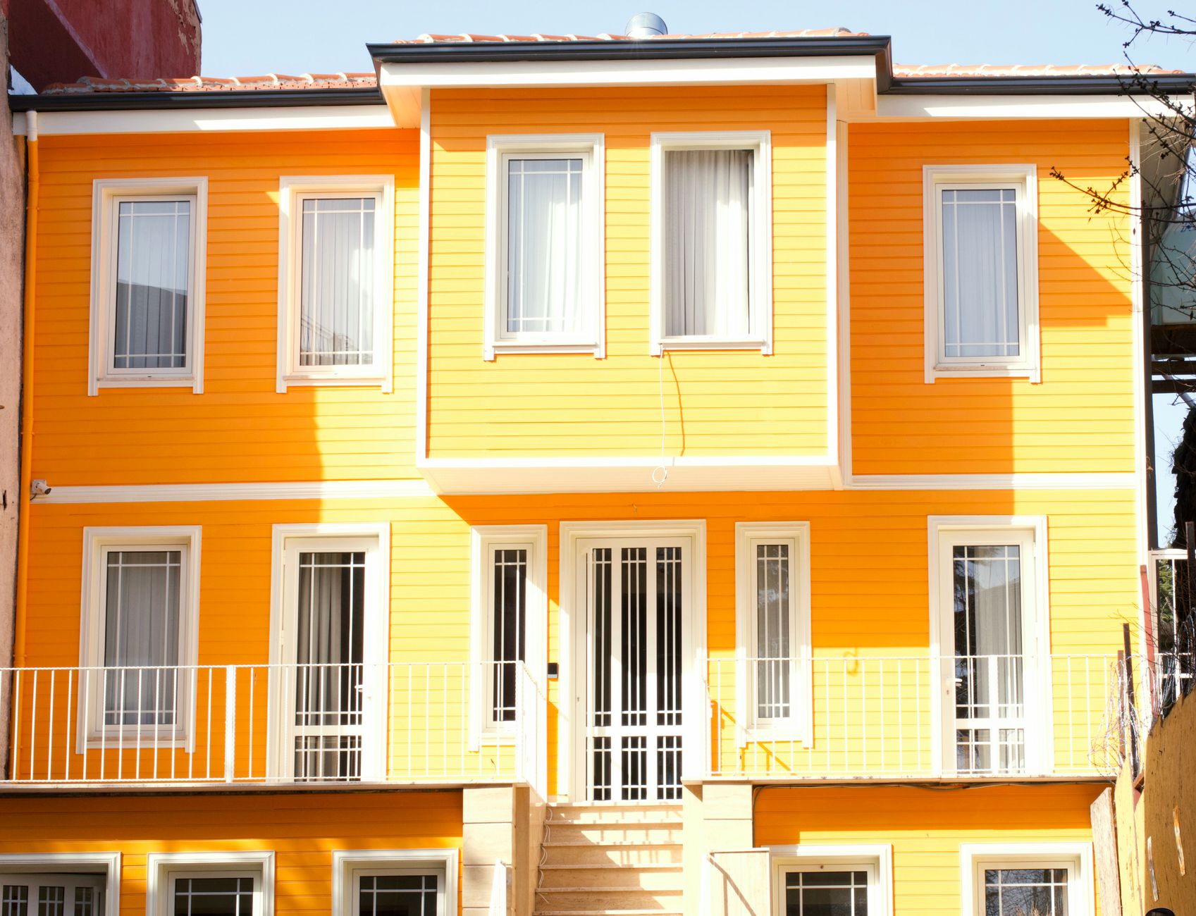 A bright yellow house exterior with white framed windows and door