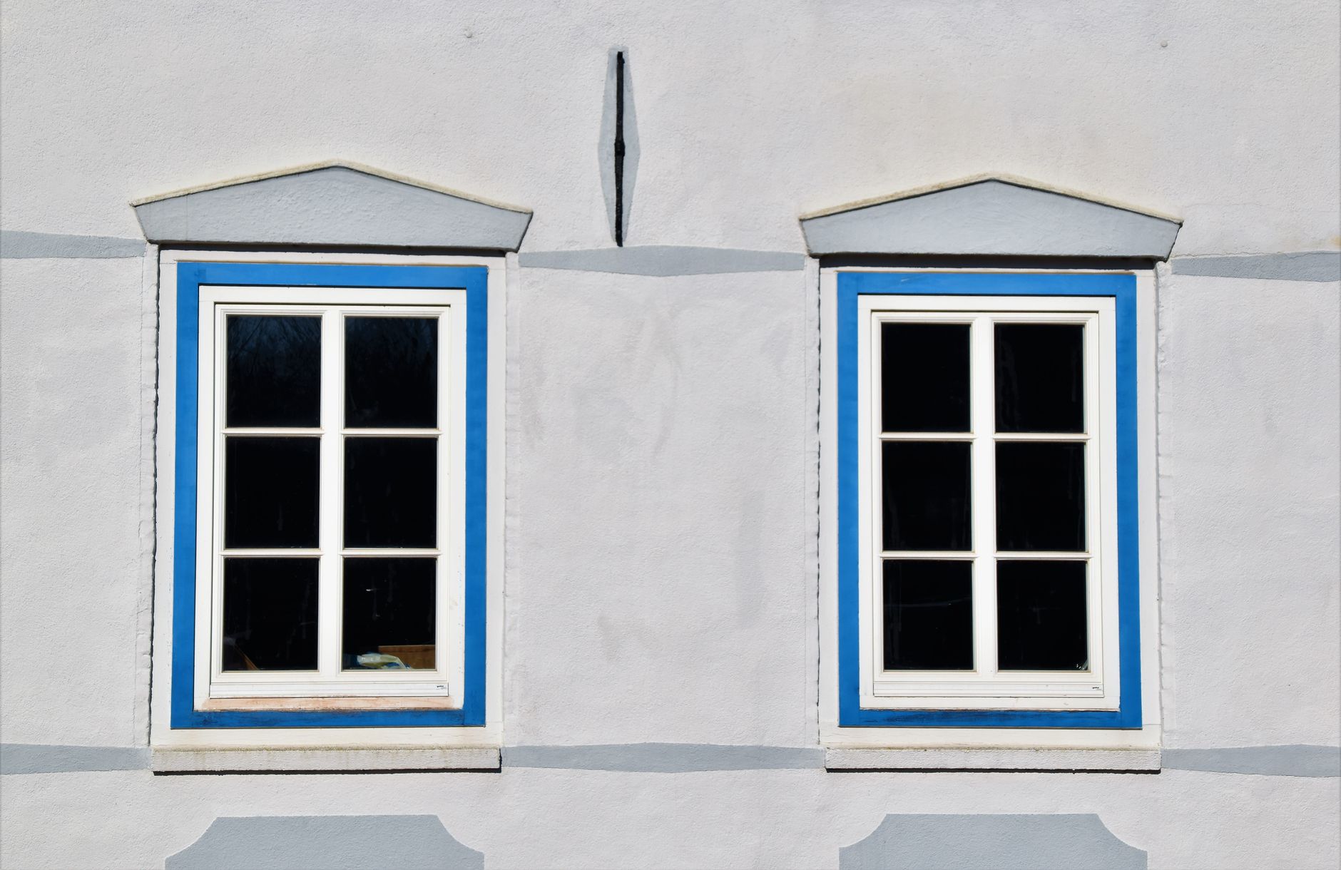 Two decorative windows with blue trim on a building in Glückstadt